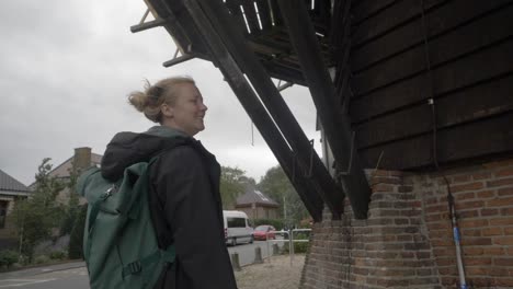 slow motion footage of a female traveler observing the architecture underneath an old windmill in the dutch countryside