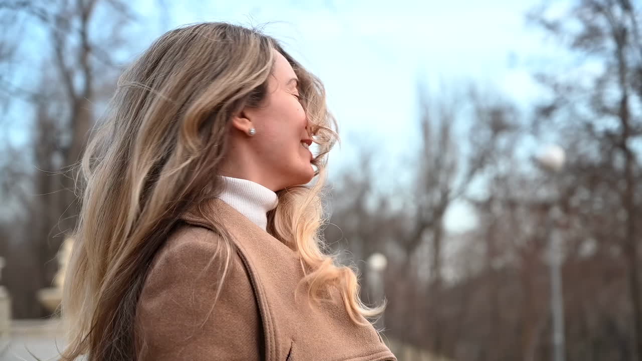 Close up of a blonde woman smiling and spinning in a park in daylight