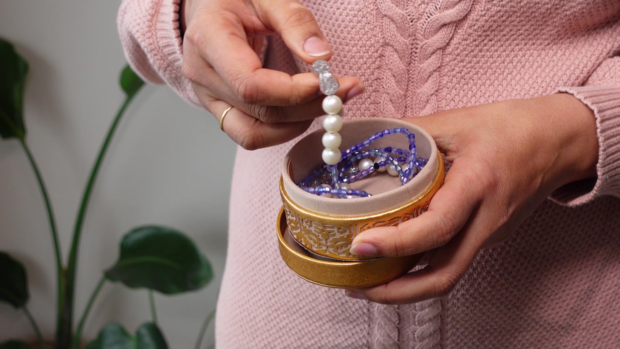 Woman's Hands Opening a Golden Jewelry Box and Taking Out a Pearl Bracelet