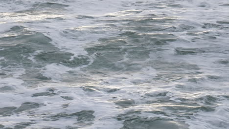 slow motion stormy ocean surface waves with sunlight shining