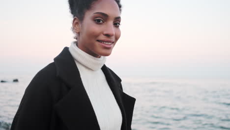 una chica afroamericana caminando por el mar.