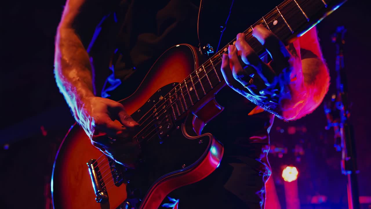 Video dinamico con inquadratura dal basso di un chitarrista che suona una chitarra elettrica, mettendo in risalto un palco vibrante.