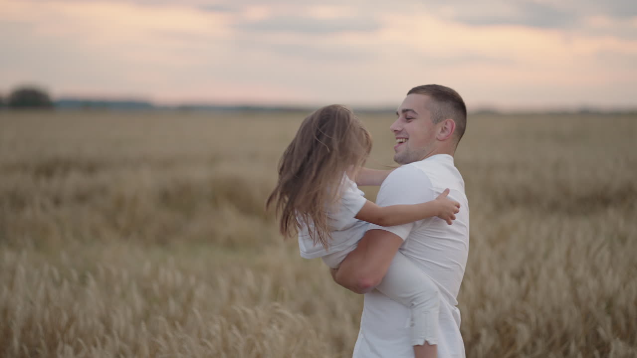 A father hugs and circles his beloved daughter at sunset. Slow motion circling at sunset in the field of a girl