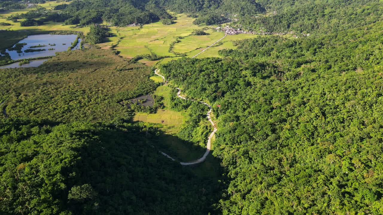 Scenic aerial flyover of hillside winding roads along lush tropical greenery during daytime at Batalay, Bato, Catanduanes, Philippines