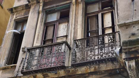 edificio antiguo con ventanas rotas y balcón oxidado