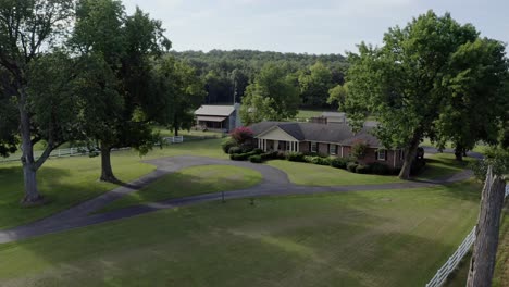 rising aerial of peaceful southern farmhouse surrounded by white fence, 4k