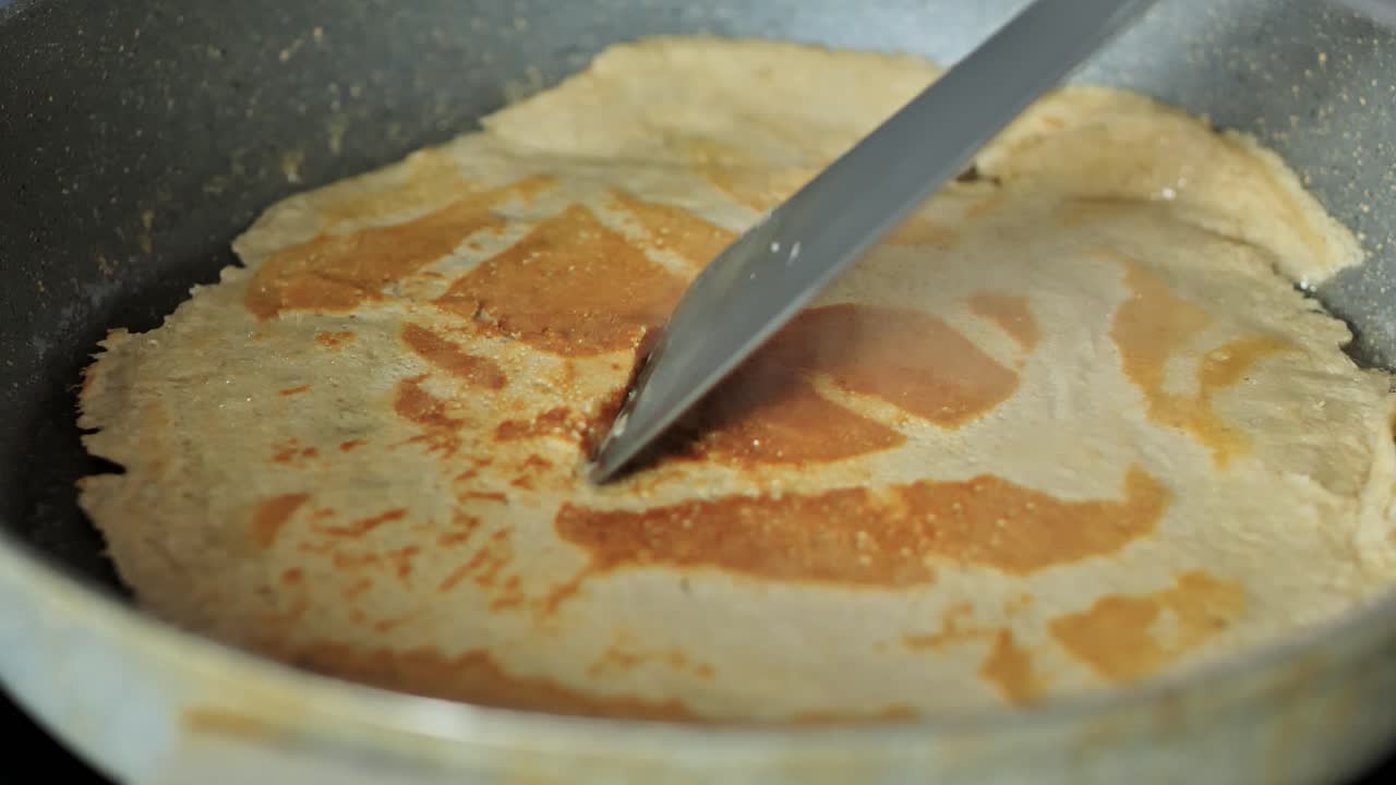 Golden pancake flips in pan capturing homemade cooking and rustic texture