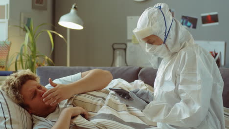 doctor in protective suit visiting sick man at home