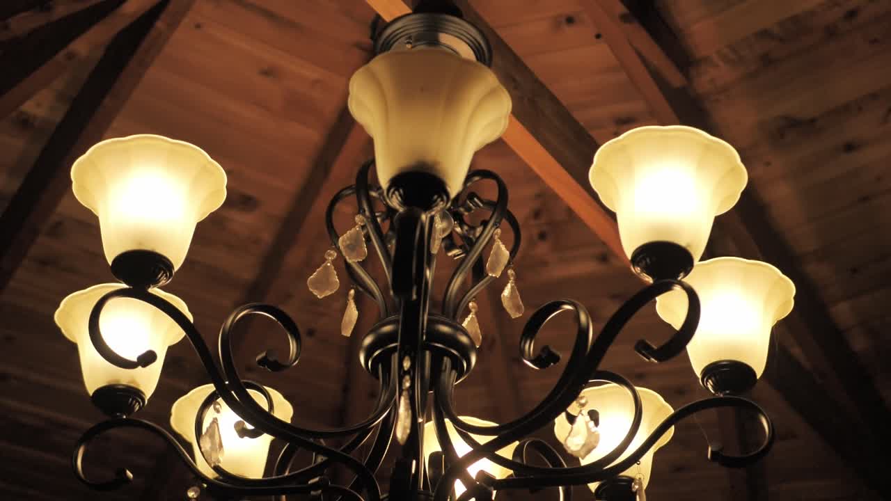 Classic Chandelier Made In Bronze With Glowing Glass Shades. Low Angle Shot