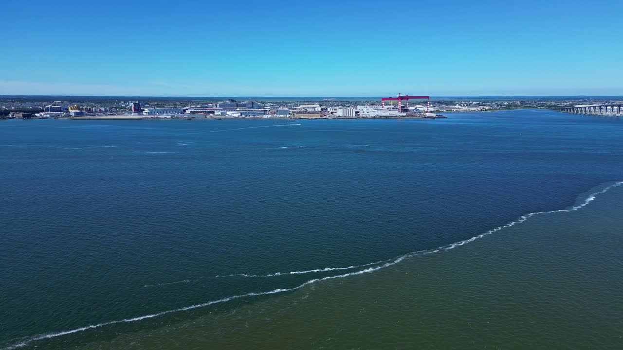 Commercial and industrial port on bank of Loire estuary, Saint-Nazaire, France. Aerial drone forward over sea and copy space