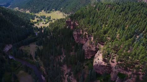 AERIAL:-Birds-eye-view-of-evergreen-valley-cliffside-being-engulfed-by-the-shadow-of-a-cloud