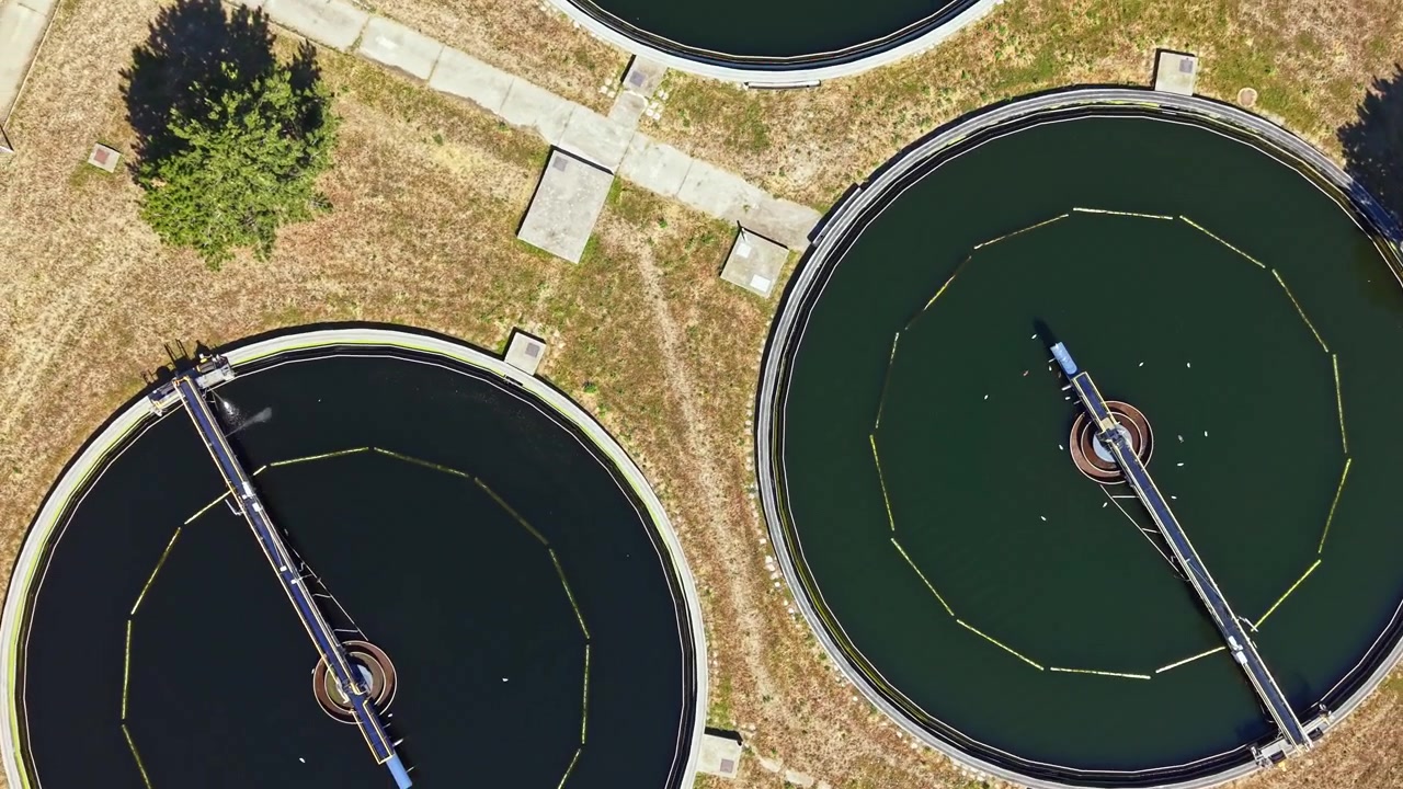 Water treatment facility with circular tanks and pathways in an industrial area during the day