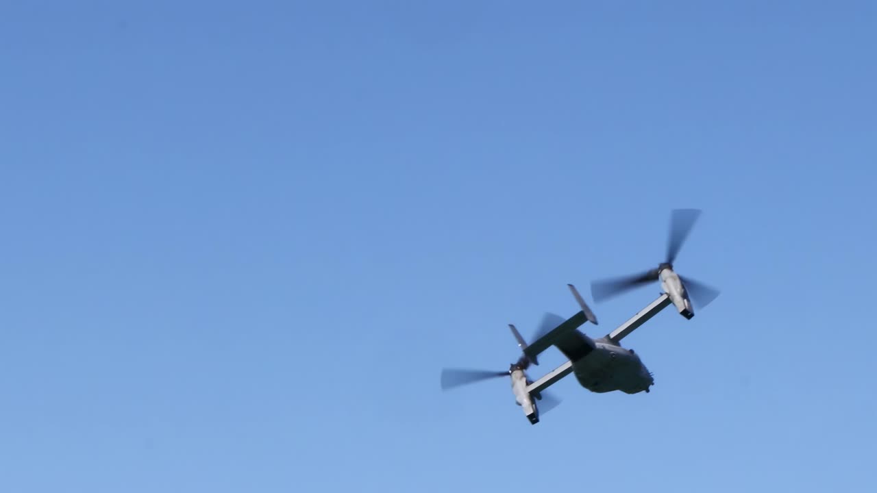 A tiltrotor aircraft executes dynamic maneuvers against a clear blue sky, showcasing its versatility and agility.