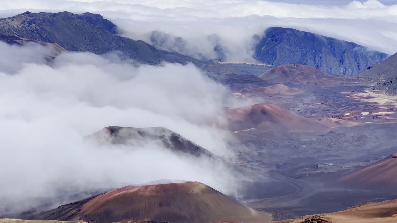 Cinematic booming up shot of clouds enveloping the volcanic crater at the summit of Haleakala in Maui, Hawai'i