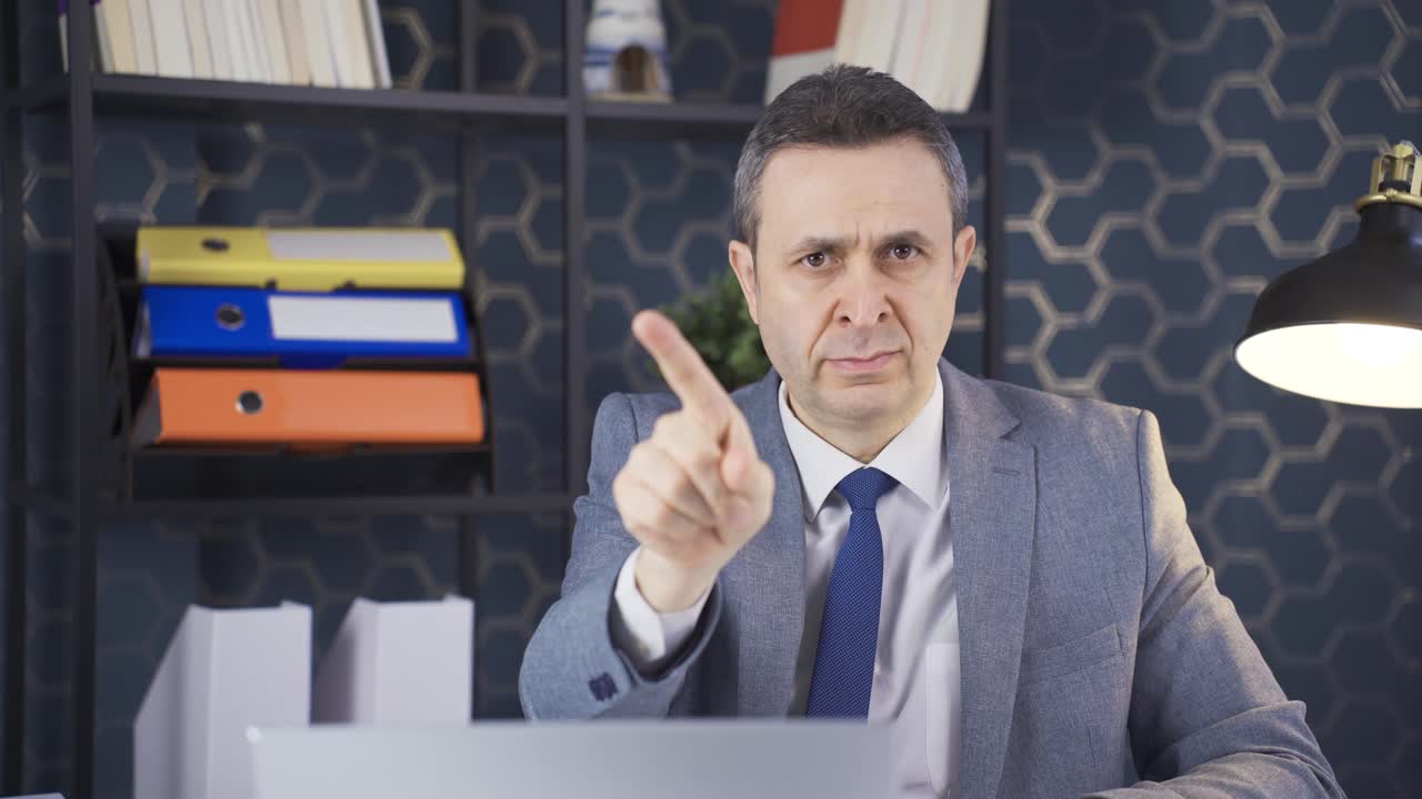 Kancelářský pracovník vrtící prstem na znamení nesouhlasu a „ne“.