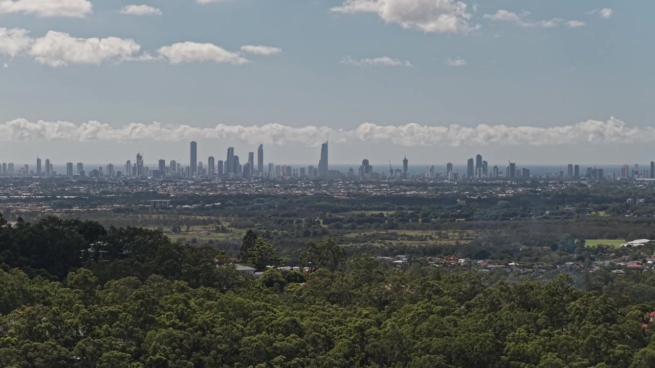 Skyline della città di Gold Coast dall'entroterra in una giornata di sole nel Queensland, Australia. Ripresa drone in allontanamento.