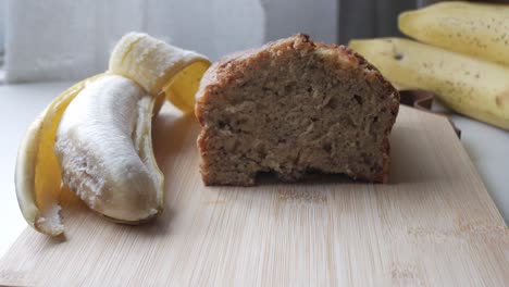freshly baked banana bread with ripe bananas on a wooden cutting board in natural daylight