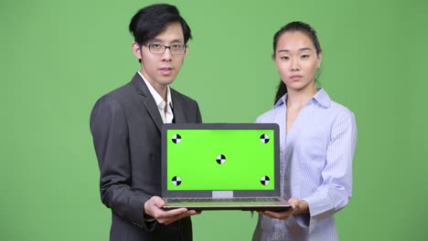 young asian business couple showing laptop together