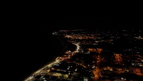 stunning 4k drone footage of the sea at night, with illuminated coastline and city lights