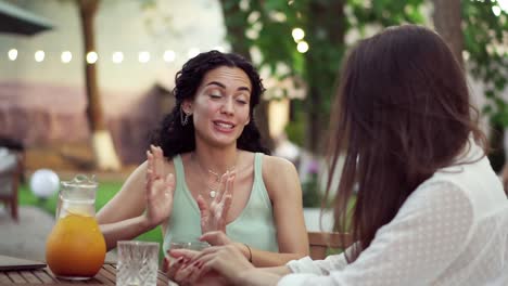 personas, comunicación y concepto de amistad - mujeres jóvenes sonrientes bebiendo jugo de naranja y hablando en una cafetería al aire libre