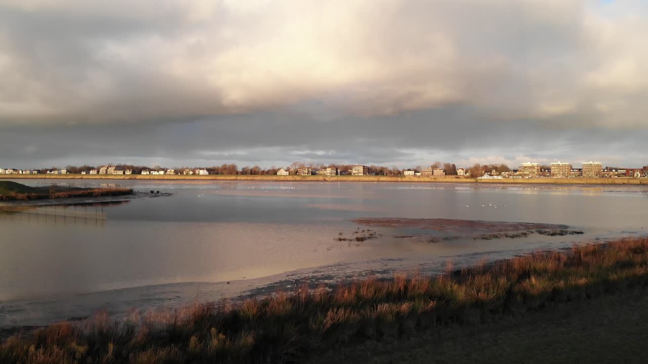 일몰 동안 잔잔한 강가에서 도시 경관을 가로지르는 클라우드스케이프