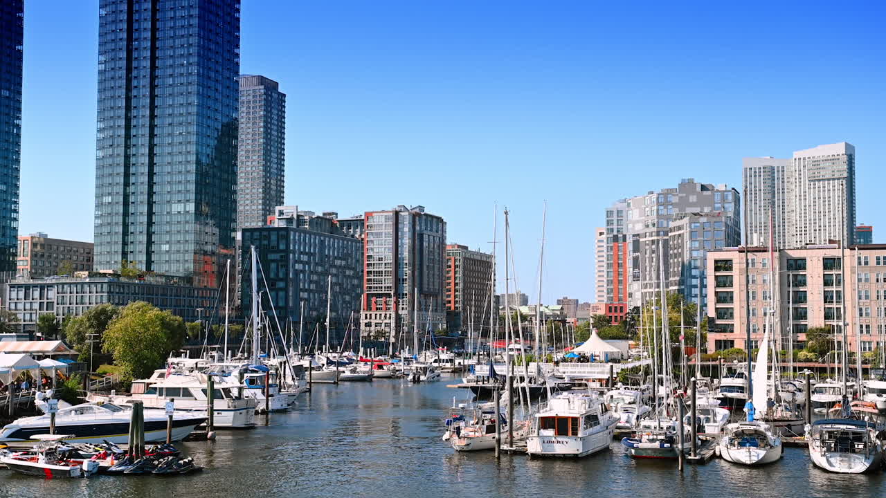 Modern marina with boats and skyscrapers. Sailboats and yachts docked in a busy marina surrounded by modern buildings on a clear sunny day