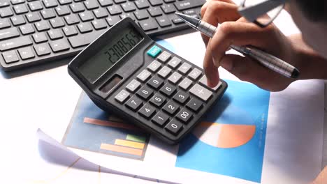 person working on a calculator and graphs