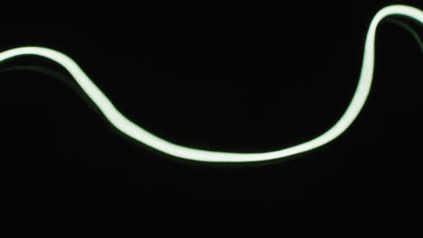 animation of white neon lights moving over black background with copy space