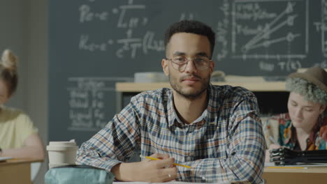 young male student with glasses in a classroom