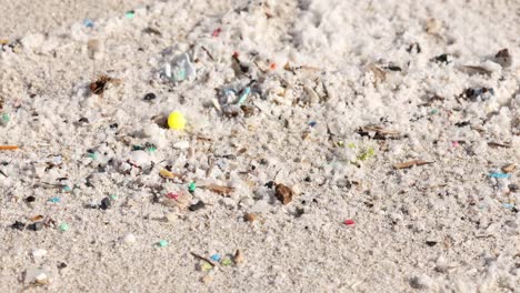 Close-up-of-microplastics-pollution-on-sandy-beach,-environmental-issue