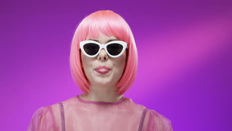 Close-Up-Of-Stylish-Woman-Wearing-A-Pink-Wig-And-Glasses-And-Chewing-Gum