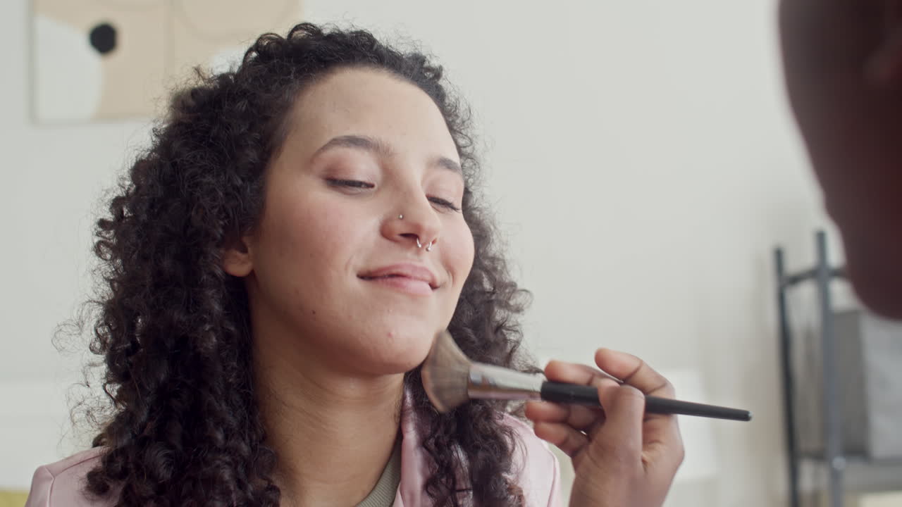 Girl Using Brush Applying Foundation on Face of Friend