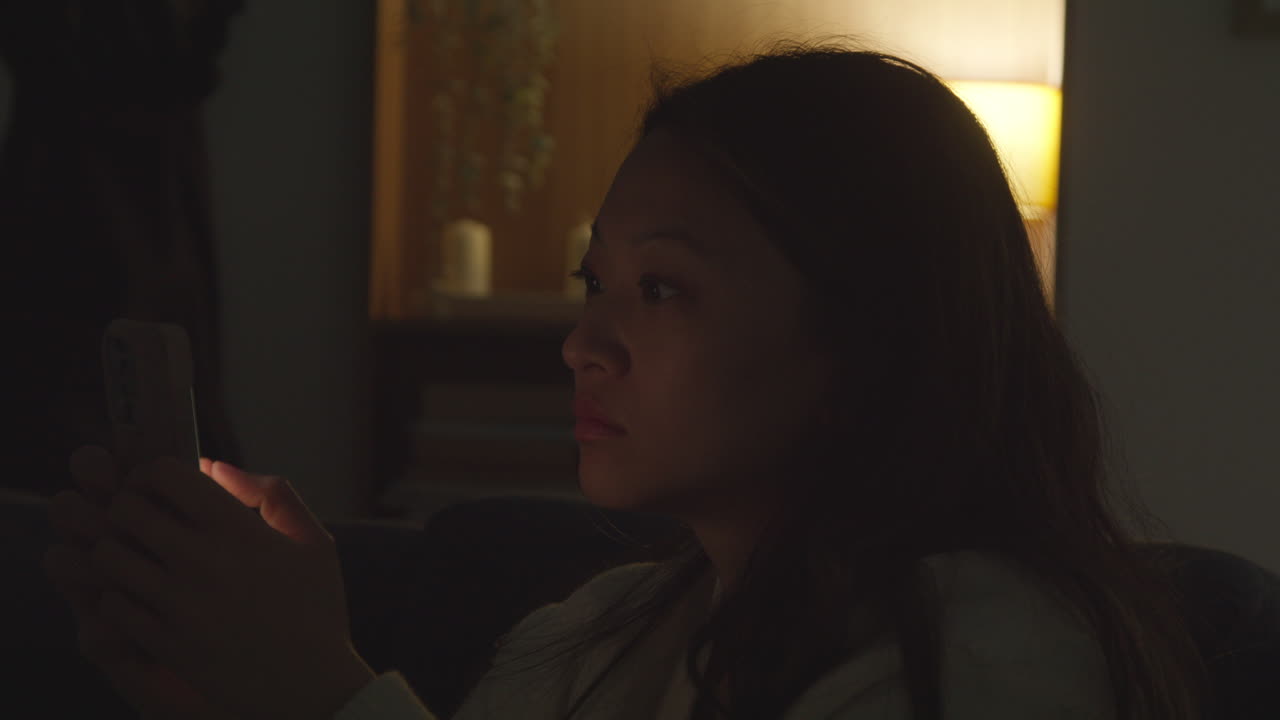 집에서 저녁을 보내고 소파에 앉아 휴대전화를 들고 인터넷이나 소셜 미디어를 스크롤하는 여성의 클로즈업 6