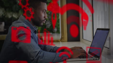 múltiples iconos digitales flotando contra un hombre afroamericano usando una computadora portátil