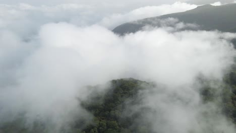 volando sobre las nubes sobre una montaña verde