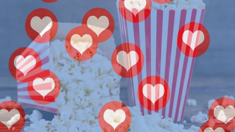 Animation-of-heart-icons-flying-over-popcorn-in-red-and-white-striped-tubs