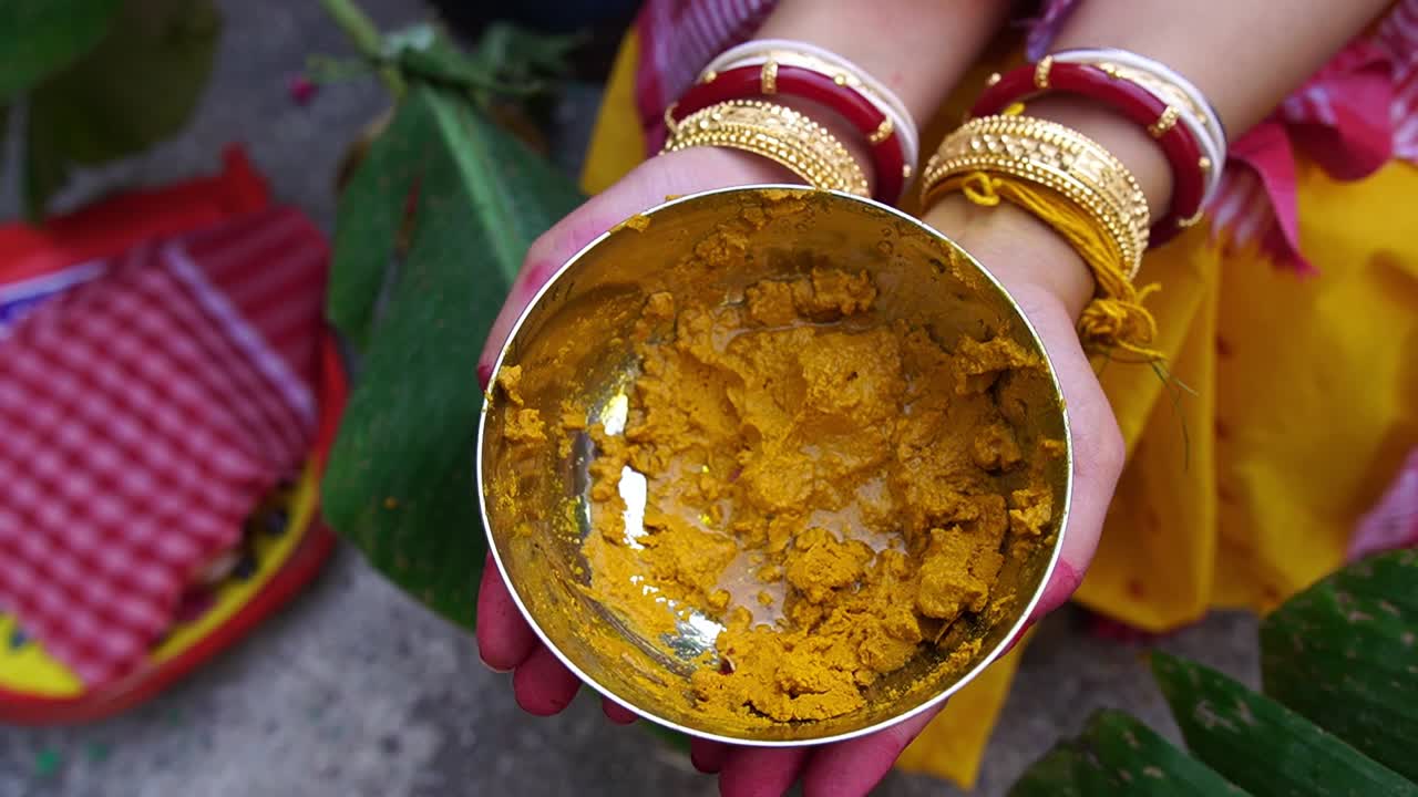 Slow motion shot of a Hindu bride holding yellow turmeric on her hands