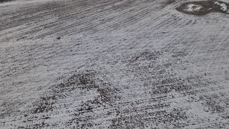 drone flying over a field covered with a thin layer of snow