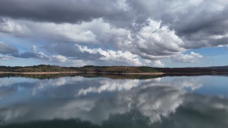 a windless morning with the clouds reflecting the on the water