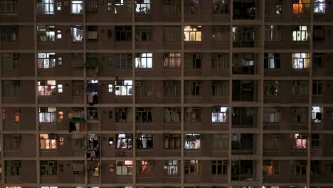 Una-Vista-Nocturna-De-Un-Edificio-De-Viviendas-Públicas-De-Gran-Altura-Lleno-De-Gente-En-Hong-Kong