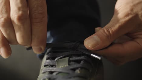 a close-up of a man's hands tying shoelaces.