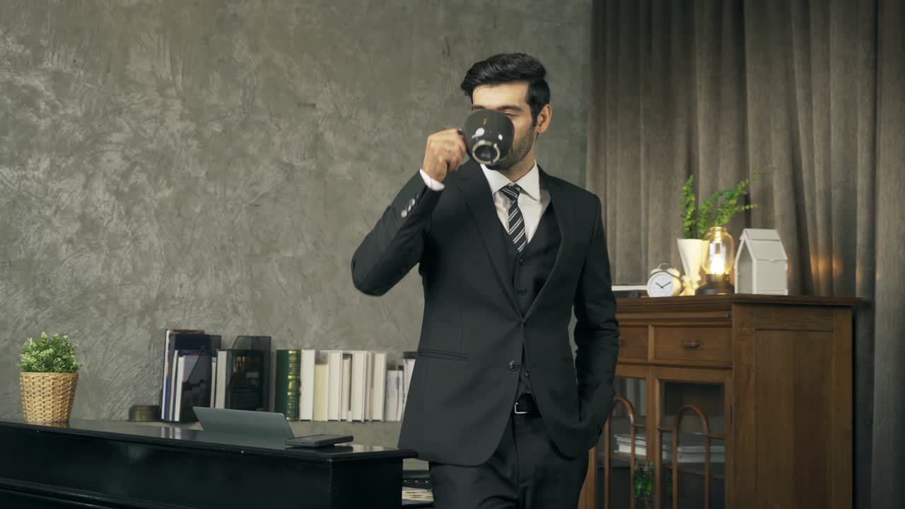 retrato de un feliz hombre de negocios sonriente de oriente medio bebiendo una taza de café, director ejecutivo o persona ceo con traje de pie en la habitación.