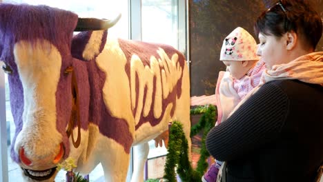 mother and baby looking at a purple cow display