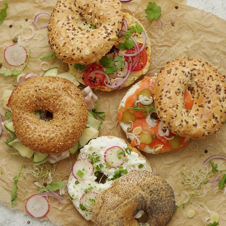 Circular bread bagel sandwich served with various toppings Samlon ham and cheese cottage hummus