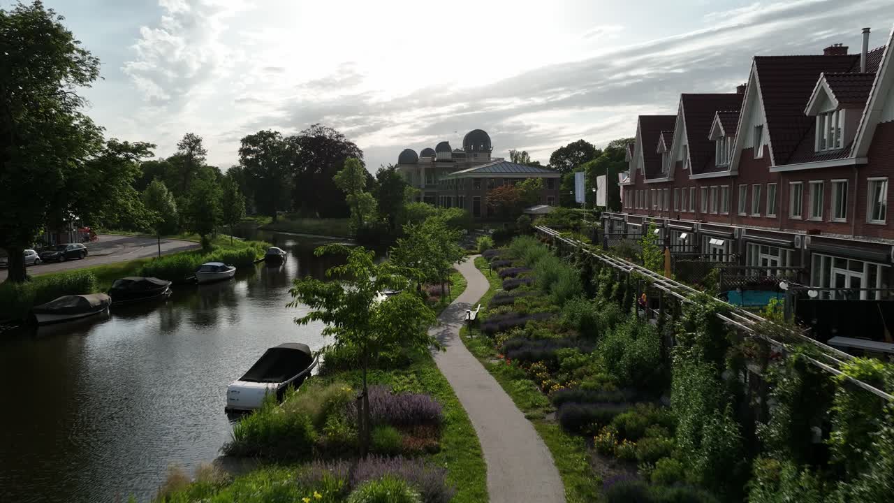 Aerial zoom in highlighting a garden pathway leading to Leiden Observatory with the cityscape in the background, Netherlands