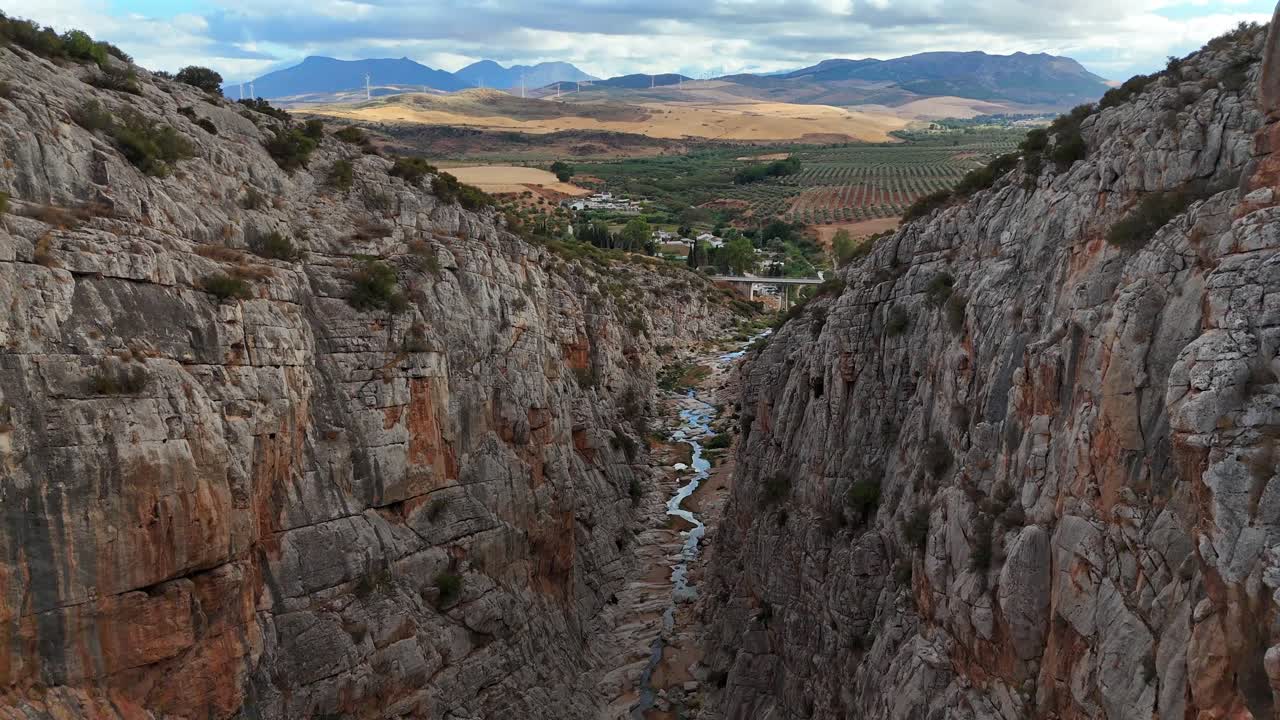 Ampia panoramica aerea del terreno aspro della sierra nel sud della Spagna: catene montuose a strati che sfumano nella foschia, oliveti che ricoprono la valle sottostante, ripresa con la luce del primo mattino.