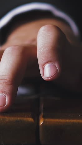 CU, slow motion: young businessman in office suit taps wooden armrest by finger sitting in retro armchair on blurred background extreme close view