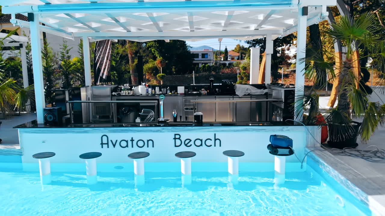 ASPROVALTA, GREECE - SEPTEMBER 25, 2020: Avaton Beach Luxury Resort from the drone. Pool with blue water, bar with chairs in water, greenery around it