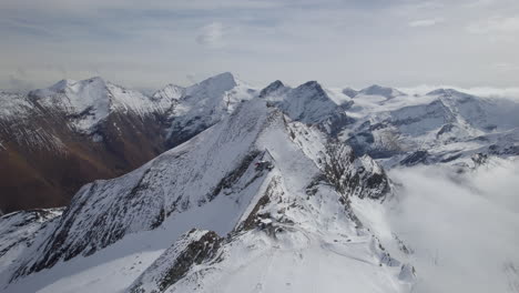 Panoramic-drone-shot-of-white-snowy-mountains-in-Austria-during-sunny-day