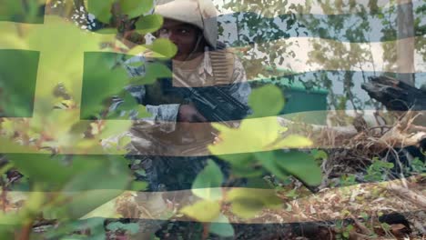 digital composition of waving greece flag against soldier with a gun keeping an eye on surroundings